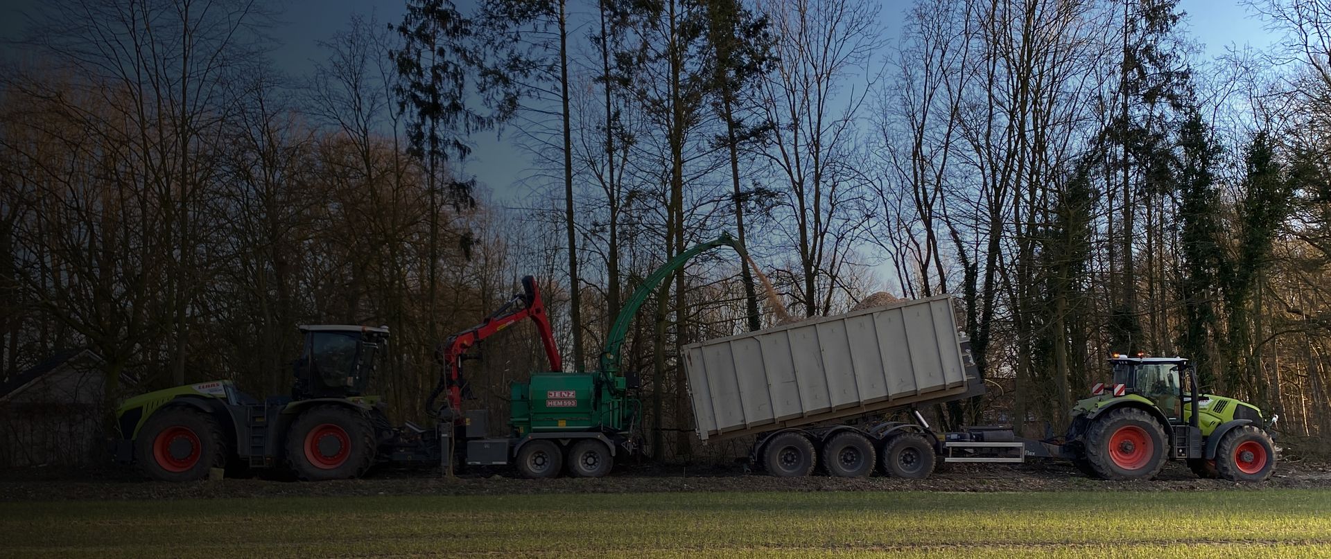 Traktoren bei Holzhäckselarbeiten am Waldrand, Hackschnitzel werden in einen Anhänger geladen